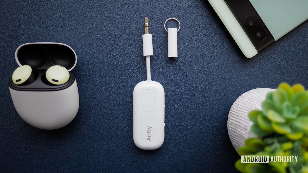 AirFly Pro on table next to earbuds in a case and a Pixel phone.